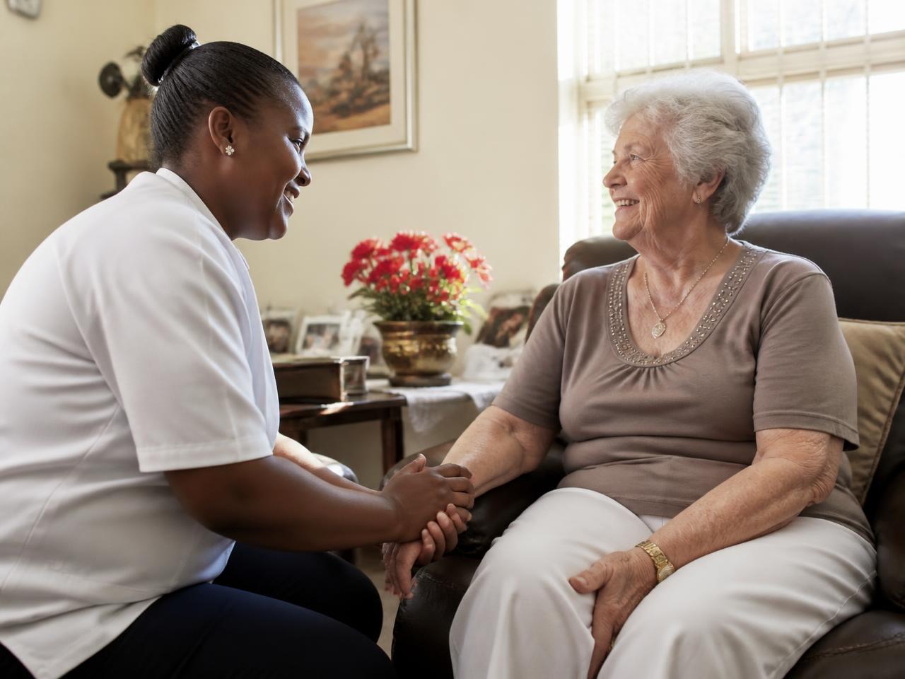 A carer sitting with an elderly client in a sunlit lounge